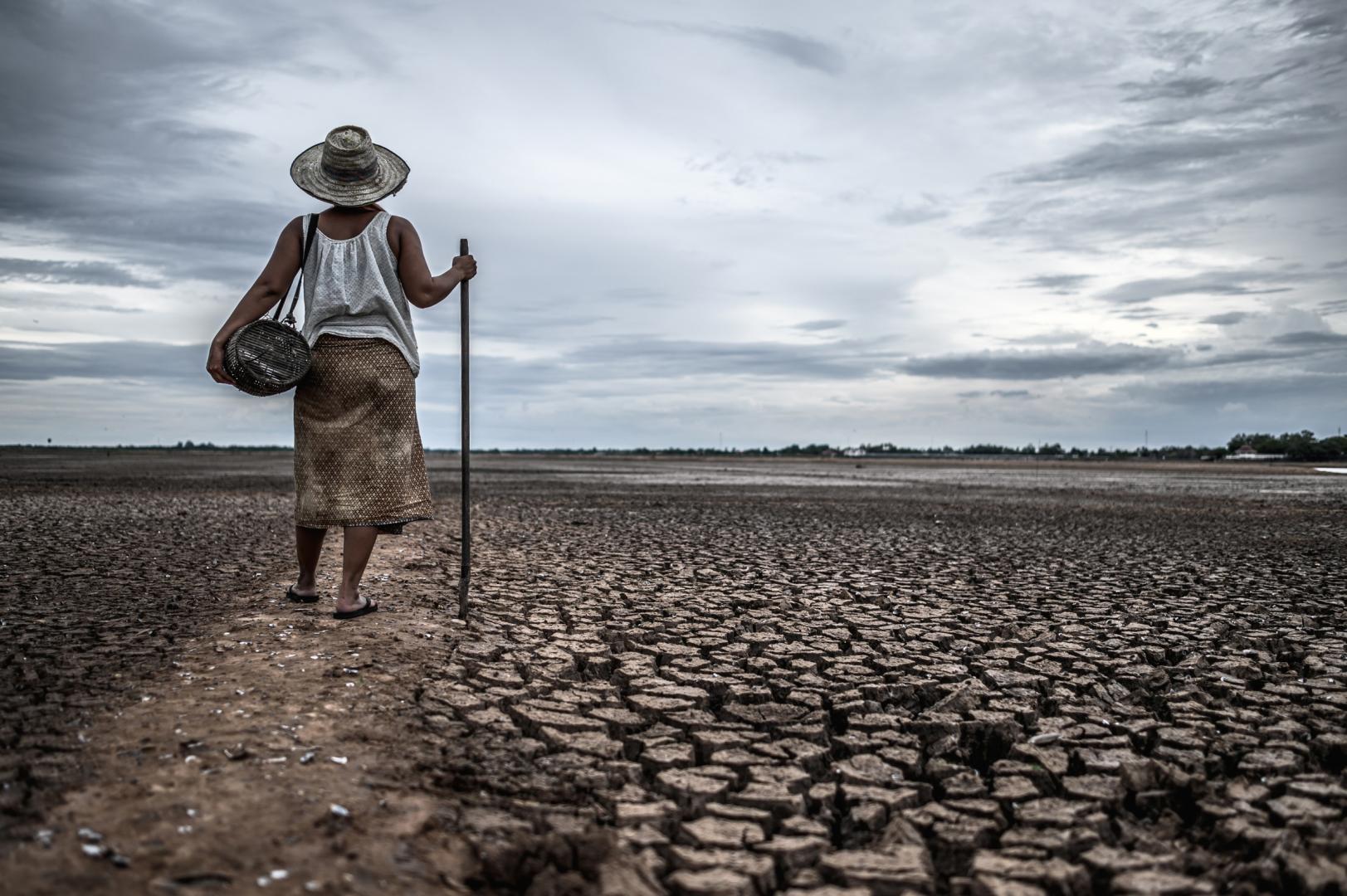 Imagen de mujer en un campo reseco que antes era un lago