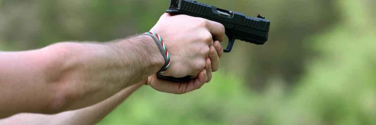 persona sosteniendo un arma de fuego