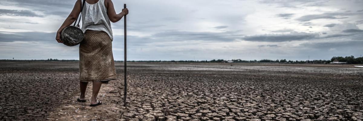 Imagen de mujer en un campo reseco que antes era un lago