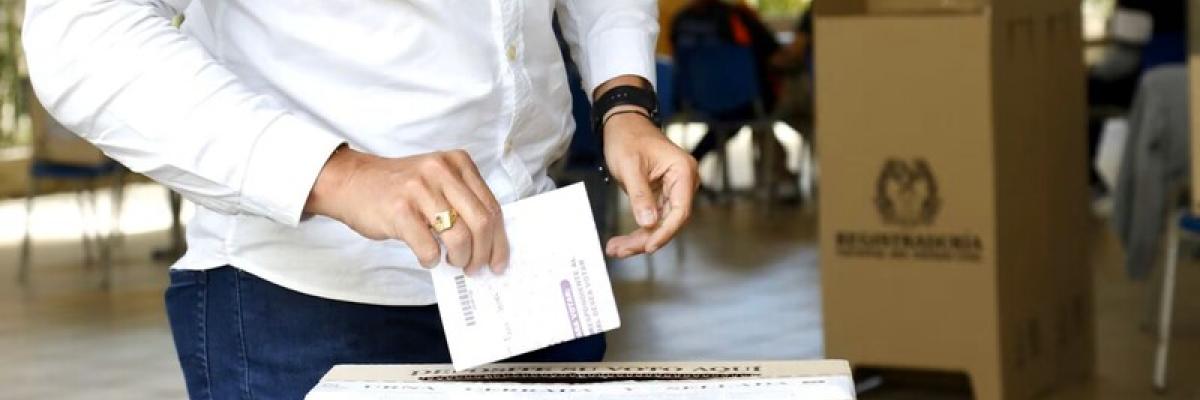 Hombre depositando su voto en una urna de votación