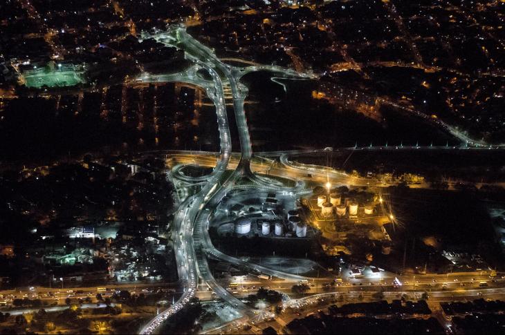 La imagen captura la magnitud del que es considerado el puente intraurbano más largo de Colombia, conectando de forma estratégica las comunas del norte (Aranjuez y Castilla) sobre el río Medellín. Las curvas de los puentes y las orejas de la intersección brillan con una intensa iluminación LED blanca, simbolizando el progreso y la conectividad de la "Ciudad de la Eterna Primavera".