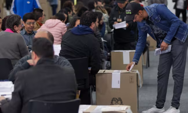 Persona ingresando el voto a la urna en puesto de votación