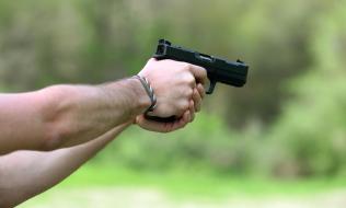 persona sosteniendo un arma de fuego