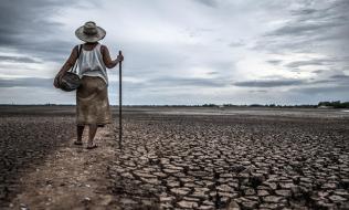 Imagen de mujer en un campo reseco que antes era un lago